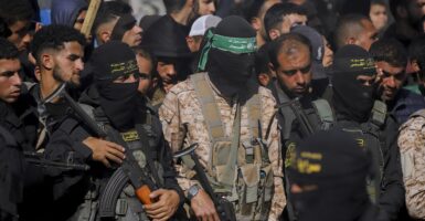 Hamas militants stand while holding machine surrounded by a crowd of people.