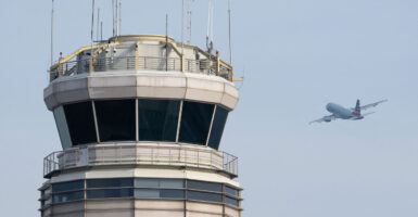 Airplanes flying past an air traffic control tower.