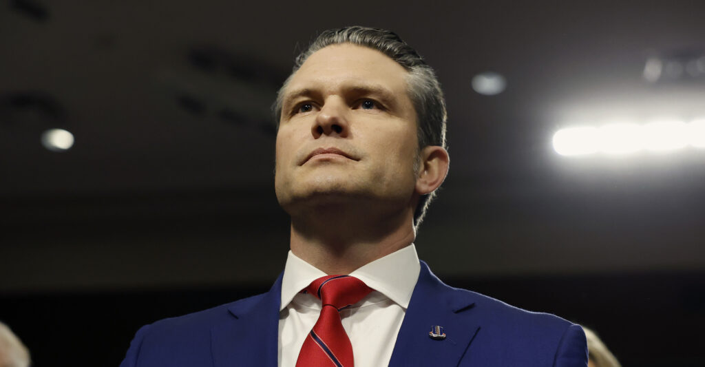 Pete Hegseth wears a blue suit and red necktie. 