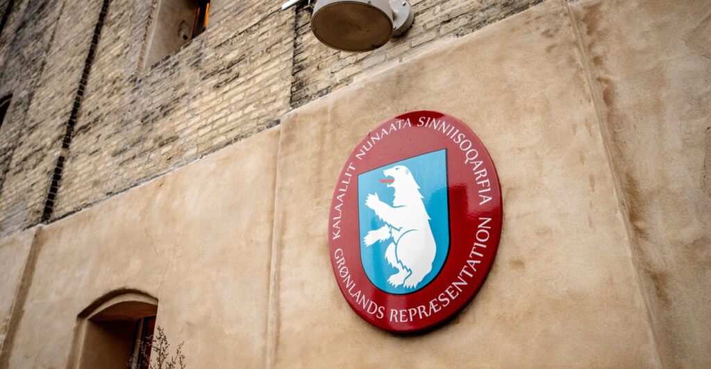 The Greenland coat of arms is on the side of a building wall.