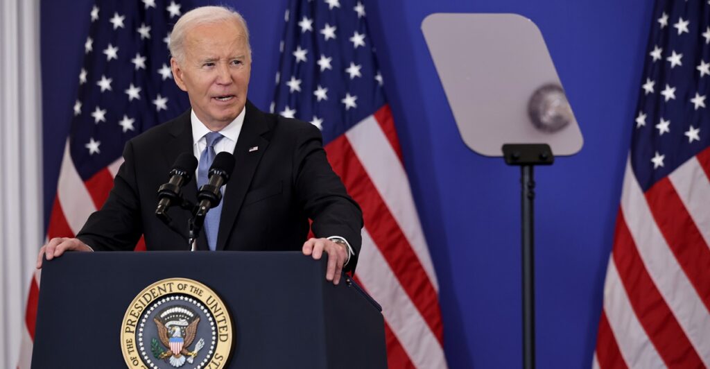 Joe Biden stands and looks to his left during a press conference.