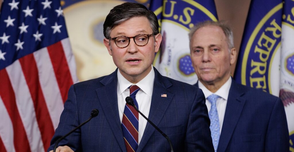 Speaker of the House Mike Johnson stands at a podium and answers questions.