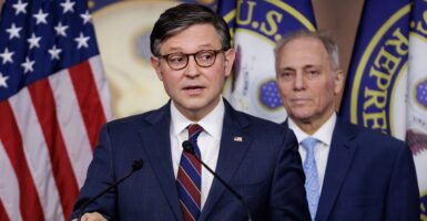 Speaker of the House Mike Johnson stands at a podium and answers questions.