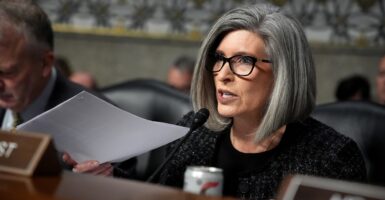 Joni Ernst sits at a table and speaks into a microphone.