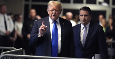 Donald Trump raises his finger in a suit.