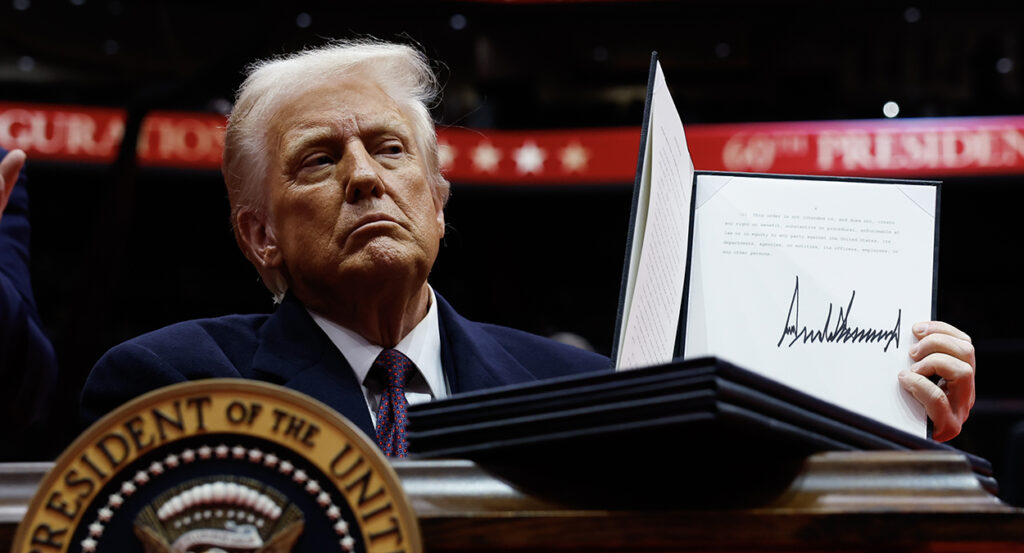 Donald Trump holds up an executive order he just signed.