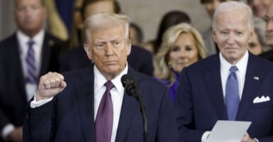 Donald Trump stands at a podium with his right hand raised in a fist.