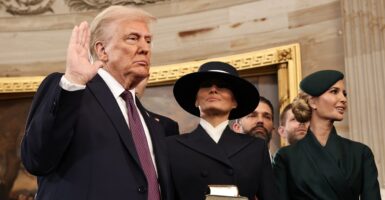 Donald Trump stands next to his wife as he raises his right hand during his swearing in ceremony.