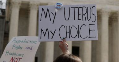 Pro-abortion protestors outside the US Supreme Court. One holding a sign saying, "My uterus, my choice."