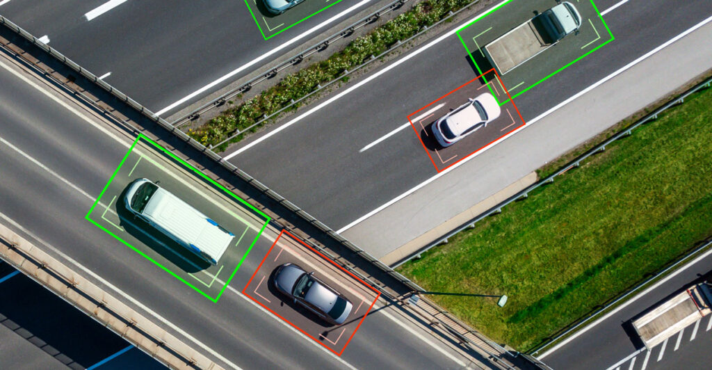 Cars on a highway photographed from the air being tracked electronically with green Or read digital boxes around Each one