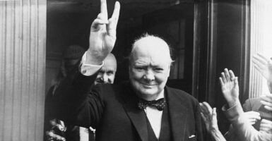 In a three-piece suit and bowtie, British Prime Minister Winston Churchill gives his famous wartime V-sign