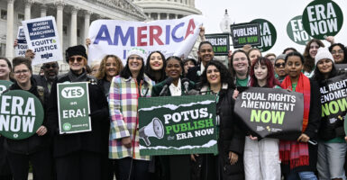 Several female protesters outside the U.S. Capitol holding up signs urging adding the equal rights amendment to the Constitution of the United States