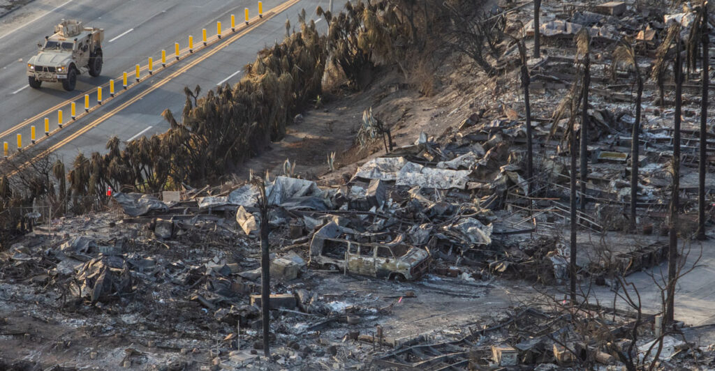 Homes totally destroyed by fire and a National Guard truck on the street next to them