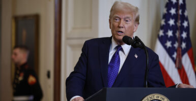 Donald Trump in a suit in front of an American flag