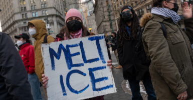 Protesters hold a sign reading "Melt ICE"