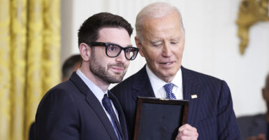 Alex Soros in a suit accepts an award from Joe Biden.