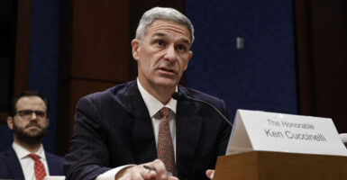 Ken Cuccinelli in a dark suit and sitting at a table testifying to a congressional committee