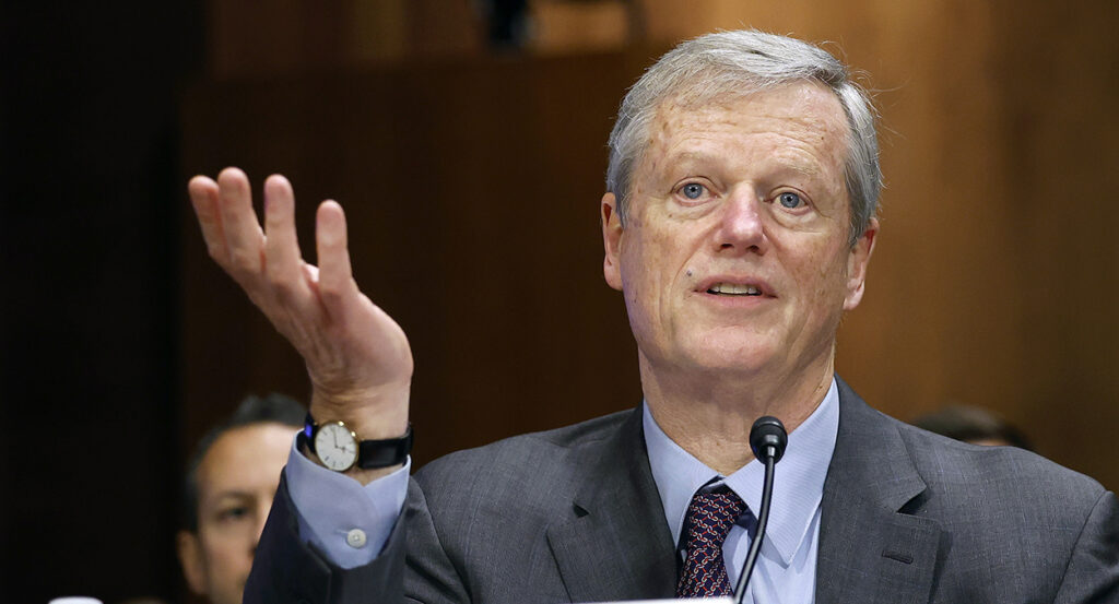 NCAA President Charlie Baker gestures in a blue and grey suit