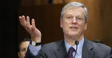 NCAA President Charlie Baker gestures in a blue and grey suit