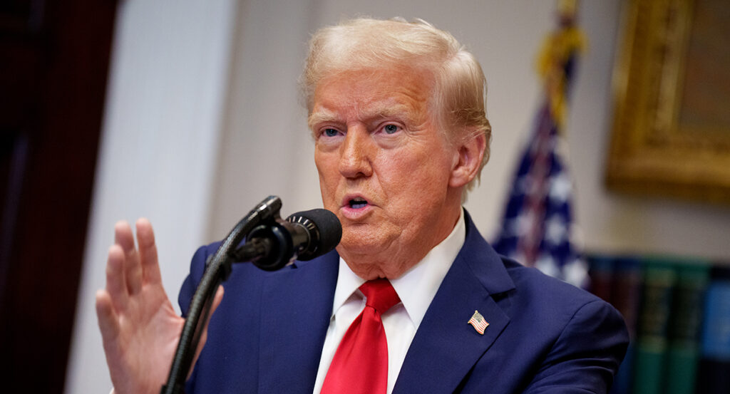 President Donald Trump gestures in a blue suit with a red tie