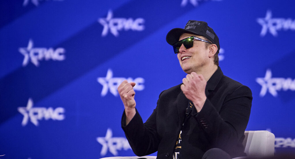 Elon Musk wearing a black Make America Great Again hat speaks at CPAC