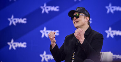 Elon Musk wearing a black Make America Great Again hat speaks at CPAC