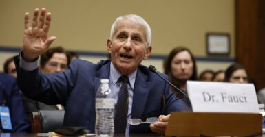 Anthony Fauci sits and raises his right hand while testifying.