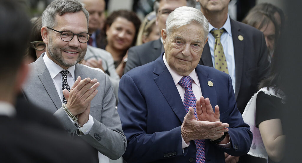 George Soros in a suit claps
