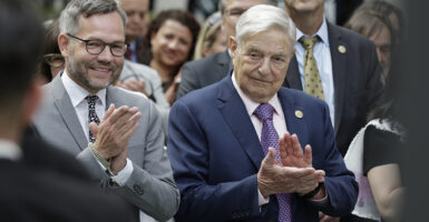 George Soros in a suit claps