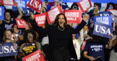 Kamala Harris, dresses in a black dress, stands among supporters for her 2024 presidential campaign.