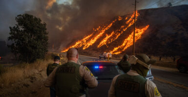 Police officers watch as flames from the Hughes Fire race up a hill in Castaic, in Los Angeles County, California, on Jan. 22.