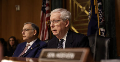 Mitch McConnell sits wearing a black suit and dark necktie.
