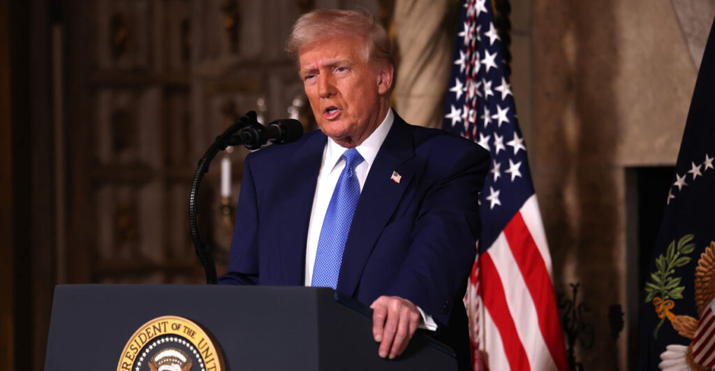 President Donald Trump speaks while standing at a podium.