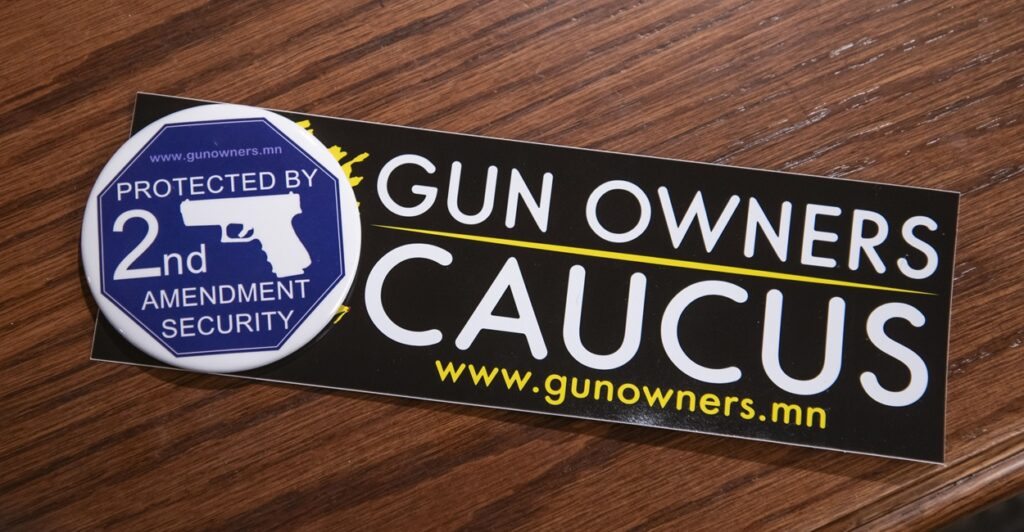 A Second Amendment sticker is on a wood table and it says "Gun Owners Caucus"