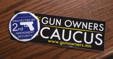 A Second Amendment sticker is on a wood table and it says "Gun Owners Caucus"