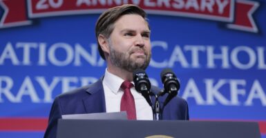 JD Vance stands at a podium and looks out at a crowd while giving a speech.