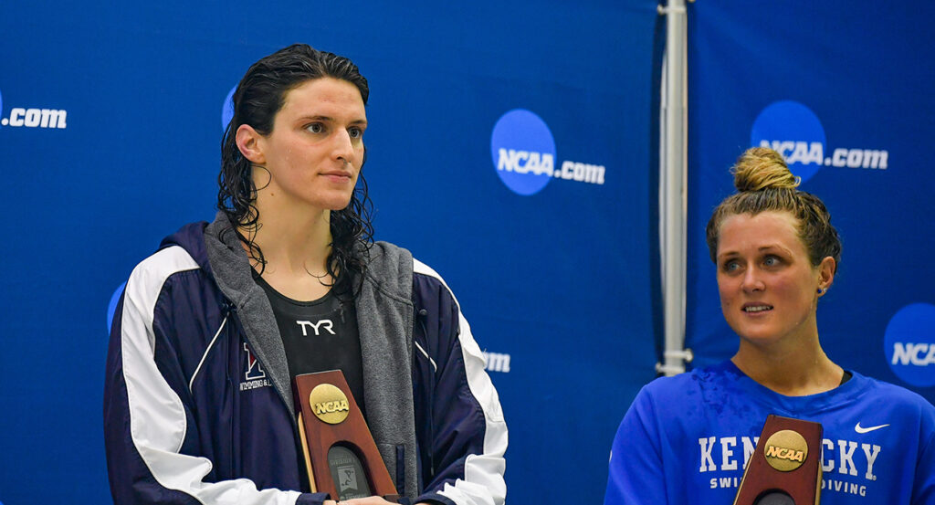 Lia Thomas and Riley Gaines stand with trophies