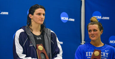 Lia Thomas and Riley Gaines stand with trophies