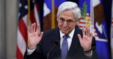 Merrick Garland in a suit raises his hands up