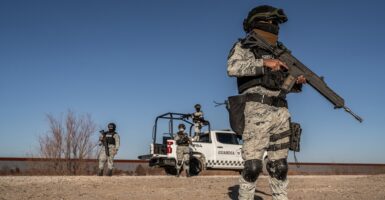 A member of the National Guard stands near the Mexico border holding a gun while dressed in military gear.