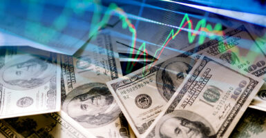 Hundred-dollar bills superimposed over a graphic of economic activity
