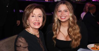 Nancy Pelosi wears formal attire and sits at a table at the Grammy Awards.
