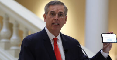 Georgia Secretary of State Brad Raffensperger holds up a cellphone at a news conference.