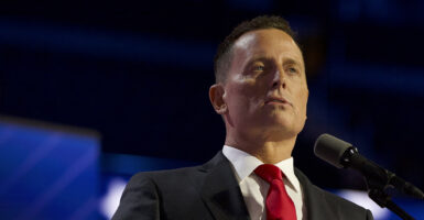Ric Grenell speaks in a grey suit with a red tie