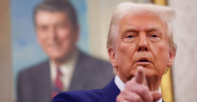 Donald Trump in a blue suit points at the camera