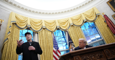 President Donald Trump and Elon Musk confer in the Oval Office of the White House.