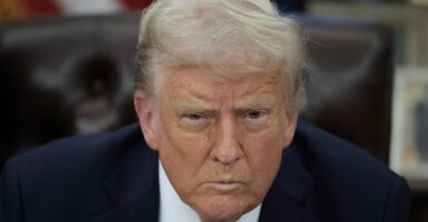 Donald Trump sits at his desk in the White House and glares ahead.