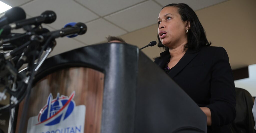 Muriel Bowser stands at a podium and speaks as she looks out in front of her.