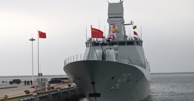 A Chinese navy ship sits at port with a flag flying.