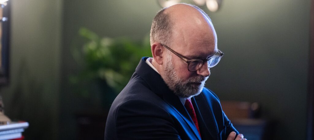 Russell Vought stands in a room with his arms folded.